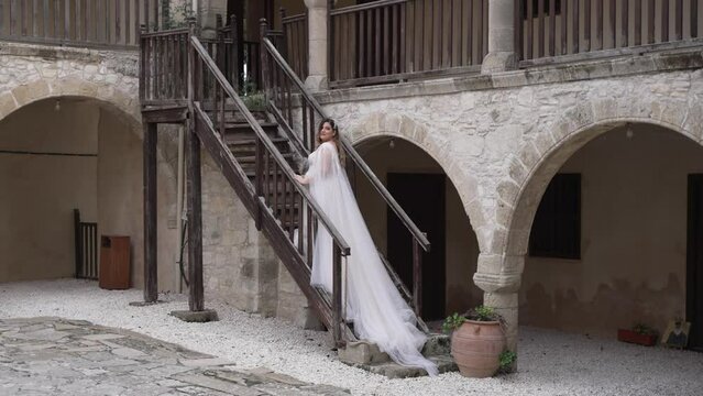 A bride poses for pictures on the steps of a Greek cobblestone villa.