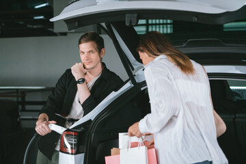 Young woman travel with EV electric car to shopping center parking lot charging in downtown city...