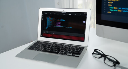 Programming code on laptop monitor and beside screen pc desktop showing website development coder....