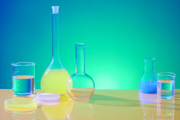 On a blue-green gradient background, glassware containing colored liquids is displayed. The laboratory space is used for advertising purposes. Front view.