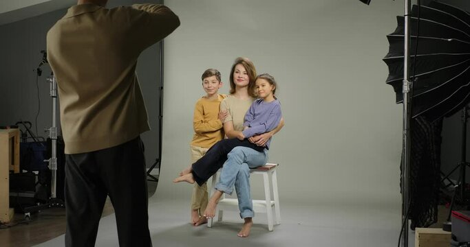Family photo shooting. Photographer takes pictures of happy family mom son daughter in studio. Family album