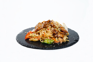 fried noodles with vegetables and meat in a flat plate on a white background, side view