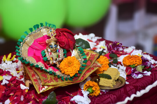 Bal Krishna Laddu Gopal, a Hindu God, is a brass statue with beautiful pink clothes and jewelry. Celebrating Krishna Janmashtami concept. Selective focus.