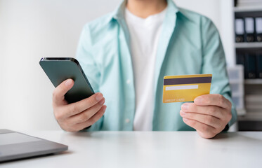 Man making financial transaction using credit card and smartphone. Young man paying online, using banking service, entering information, shopping, ordering in internet store, doing secure payment.