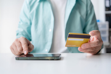 Man making financial transaction using credit card and smartphone. Young man paying online, using banking service, entering information, shopping, ordering in internet store, doing secure payment.