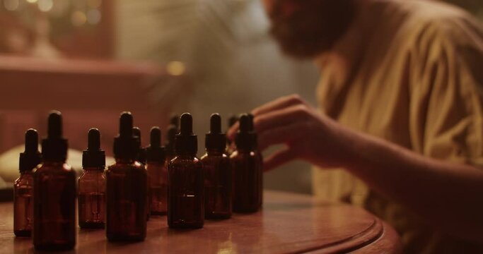 Male perfumer smelling scent of oil in dark room