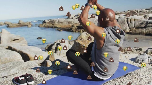 Animation Of Emoji Icons Over Senior African American Man Meditating On Beach