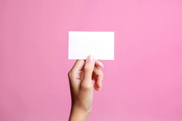 White blank card for mockup in woman hand isolated on a pink background