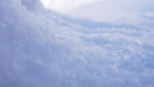 4K close up footage, capturing fresh powder snow falling on top a snow mound, in an icy cold winter landscape setting.