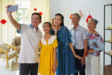 Happy Vietnamese family posing for group selfie at Tet party