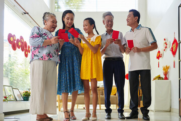 Excited family members exchanging lucky money envelopes when celebrating Tet