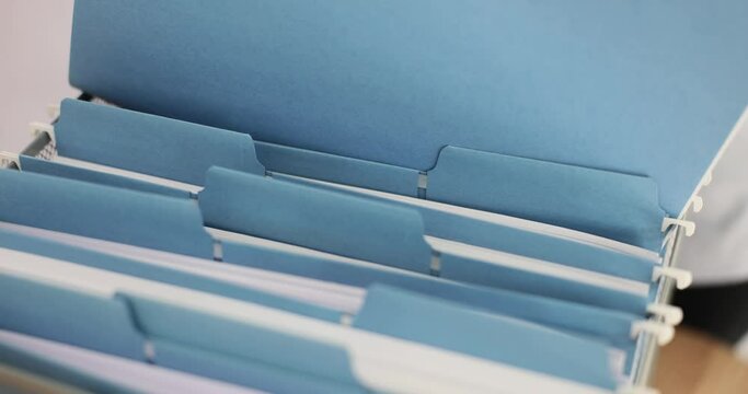 Woman office employee inserts documents in blue folder into box