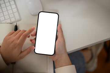 Top view image of a woman is using her smartphone at her desk. A white-screen smartphone mockup.
