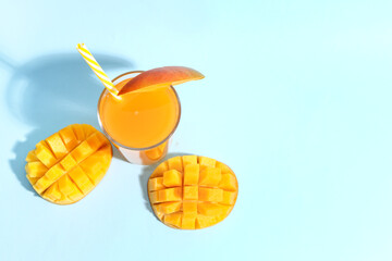 Glass of fresh mango smoothie on blue background