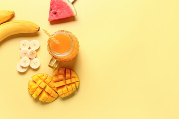 Mason jar of fresh mango juice with banana and watermelon on yellow background