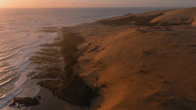 Aerial: The Hokianga Harbour and giant sand dune at sunset. Opononi, Northland, New Zealand.