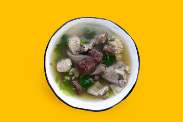 Bowl of pork blood soup on yellow background.