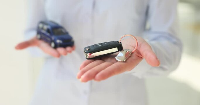 Car showroom employee offers key to customer holding car model