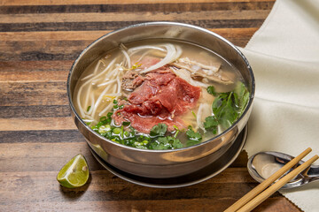 Hanoi rare Beef Pho topping with onion, noodles, green onion, lemon and coriander served in bowl...