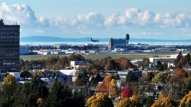 Airplane Landing On Runway Of YVR Airport In Richmond, BC, Canada. Autumn Colors In Foreground. aerial sideways shot