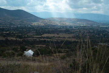 Paisaje. Casa blanca mirando al pueblo con rayos de sol de entre las nubes., desde un cerro.