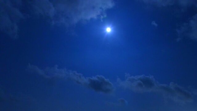 파란 밤 하늘에 하얀 달이 떠 있고 구름이 빠르게 지나가는 미속 촬영 영상