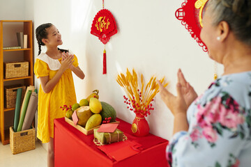 Excited girl looking at Tet decorations on walls in apartment of her grandmother