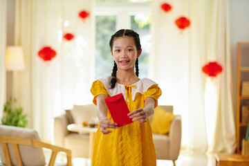 Cheerful girl giving red lucky money envelope as Lunar New Year present