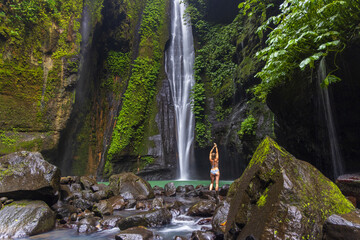 A young woman in swimming suit is posing at Hidden Waterfall near Sekumpul, Bali Island, Indonesia