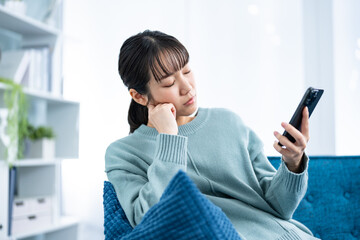 暗い表情で携帯を持つ女性