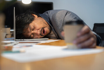 Asian tired staff officer man sleeping while using desktop computer having overwork project...
