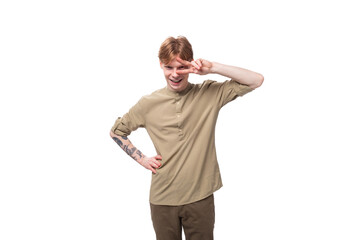 young cheerful caucasian man with red hair is dressed in a khaki shirt and brown trousers