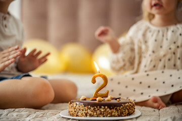 A birthday cake with candle with children celebrating birthday.