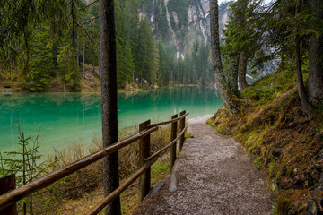 landscape of mountain lake Braies in the Dolomites, Italy. Hiking trail along the lake. Rainy spring day
