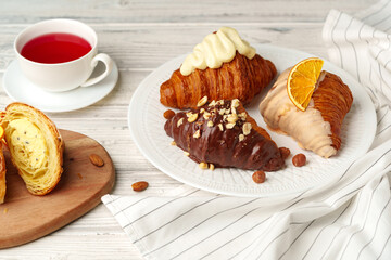Fresh croissants with cup of tea on table