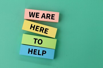 colored paper with the words WE ARE HERE TO HELP. service concept