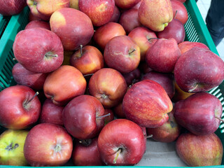 Red apples in a green basket on a market stall, close up