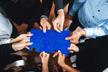 Top view multiethnic business people holding jigsaw pieces and merge them together as effective...