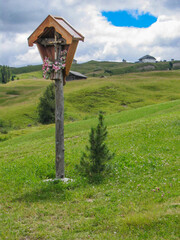 scenic view to a religious cross in the dolomites with hut in backgroud