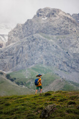 Naklejka na ściany i meble boy with a backpack on a hike against the backdrop of the mountains. child traveler with backpack, hiking, travel, mountains in the background, kids summer vacation.