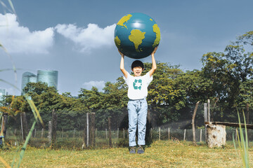 Young asian boy holding big planet Earth globe at natural park with sky background as Earth day to...
