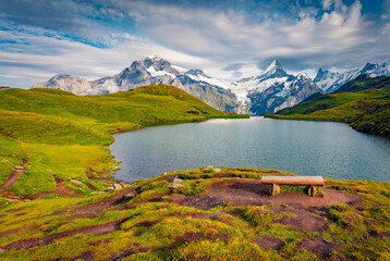 Empty bench on the shore of Bachalpsee lake with Schreckhorn peak on background. Splendid morning scene of Swiss Bernese Alps, Switzerland, Europe. Beauty of nature concept background..