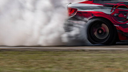 Blurred car drifting diffusion race drift car with lots of smoke from burning tires on speed track,...