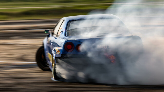 Blurred car drifting diffusion race drift car with lots of smoke from burning tires on speed track, Professional driver drifting car on race track with smoke.