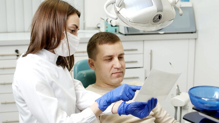 A man having a consultation and treatment with a female dentist in a professional dental clinic. Dentistry and dental services.