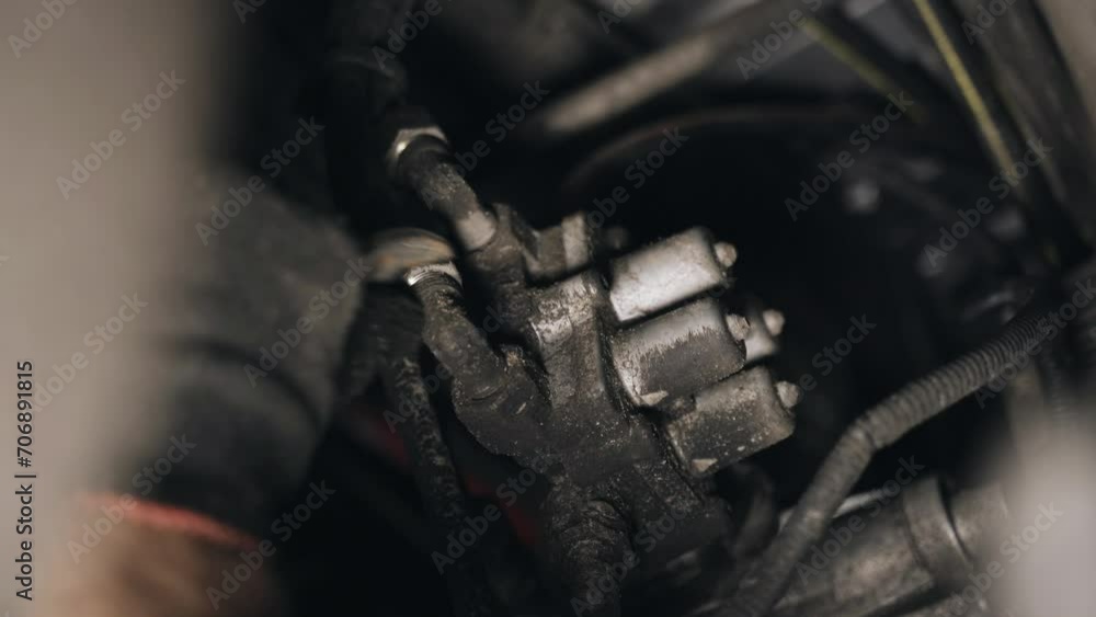 Poster A mechanic unscrews the nuts with a tool to remove a part attached to the chassis of a truck. Close-up.