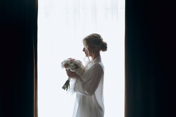 Morning of the bride, where she gets ready for a wedding in a beautiful luxury hotel in a robe with stylish hair and makeup, and then puts on a white wedding dress.