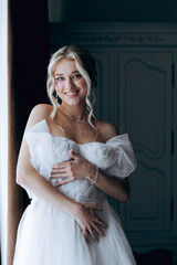 Morning of the bride, where she gets ready for a wedding in a beautiful luxury hotel in a robe with stylish hair and makeup, and then puts on a white wedding dress.