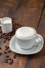 Cappuccino coffee in a white porcelain cup on a wooden table