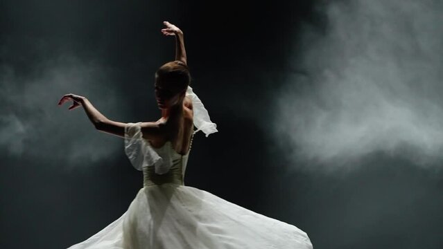 Dramatic dance, graceful ballerina in a white tutu, ballerina perform choreographic elements on a black background, beautiful windy dance, slow motion.